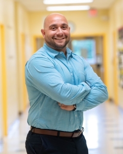assistant principal james marotta standing in a hallway with arms crossed